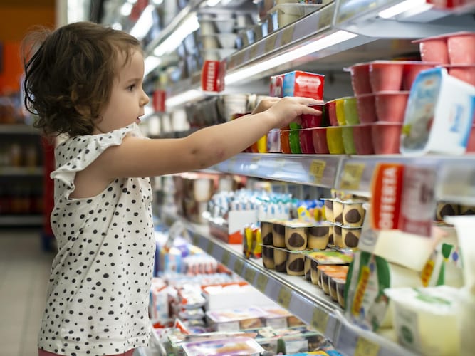 Une petite fille est attiré par l'emballage coloré d'un produit au supermarché.