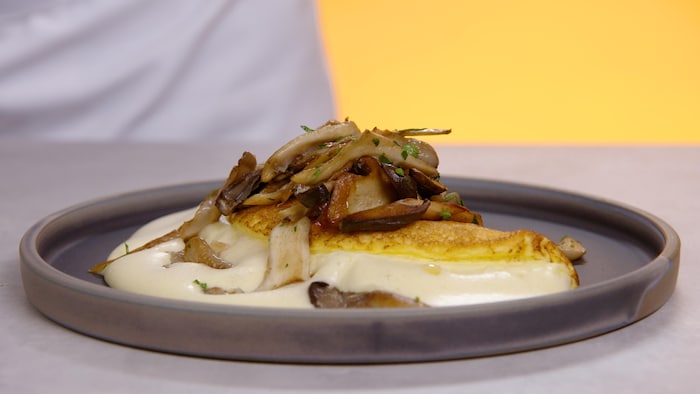 Une omelette soufflée au fromage garnie de champignons sautés, servie dans une assiette.