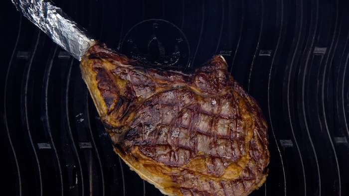 Un steak tomahawk qui cuit sur le barbecue.