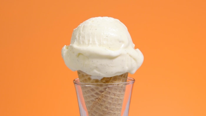 Un cornet de crème glacée à la vanille dans un support en verre.