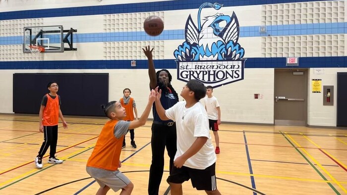 Una entrenadora de baloncesto con un grupo de estudiantes.