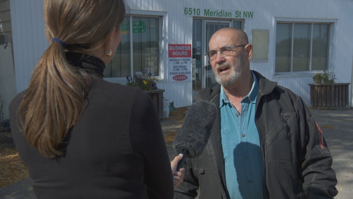 Homme en entrevue, devant son commerce, à Edmonton.