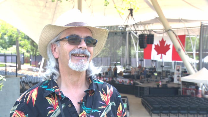Un homme devant la scène d'un concert en plein air.