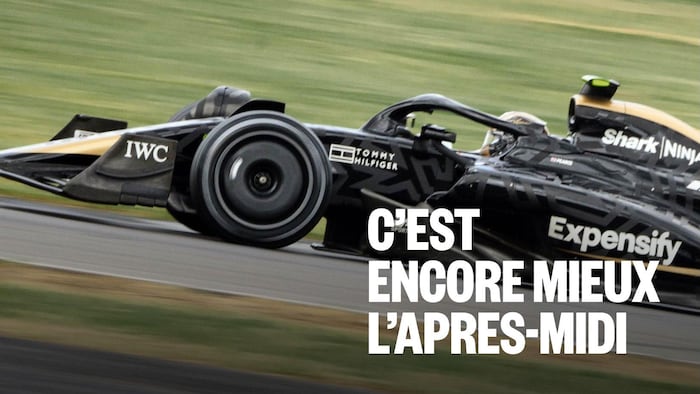 Une monoplace style F1 de profil roule sur un circuit.