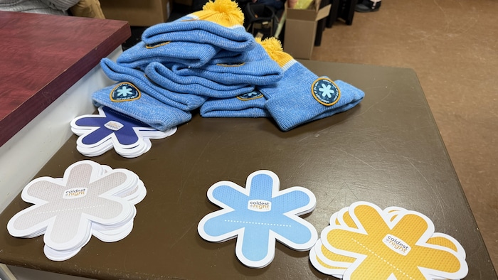 Tuques et flocons colorés jaune, bleu et gris sont disposés sur une table.