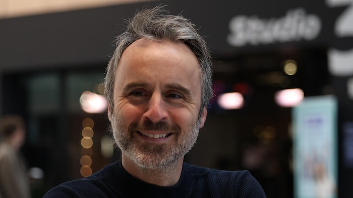 Il sourit debout devant un studio radio