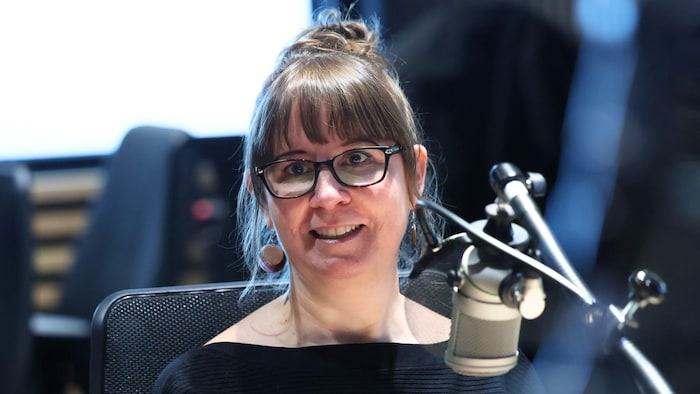 Anne Ploiurde sourit devant un micro de radio.