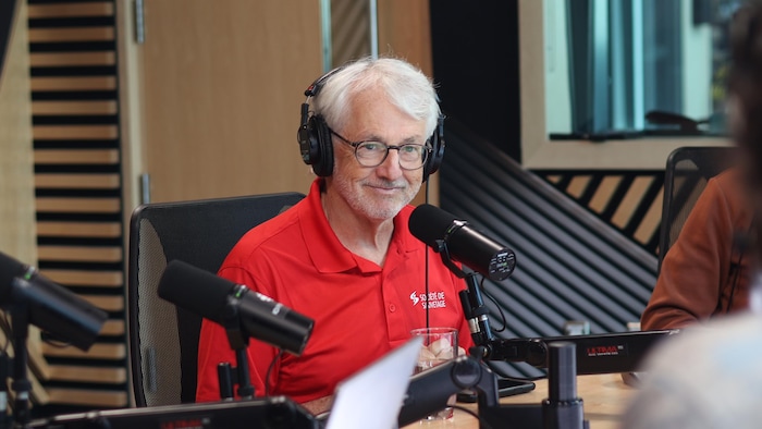 Il sourit devant un micro de radio.