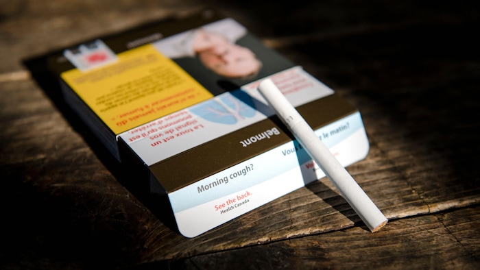 Un paquet de cigarettes et une cigarette posés sur une table. 
