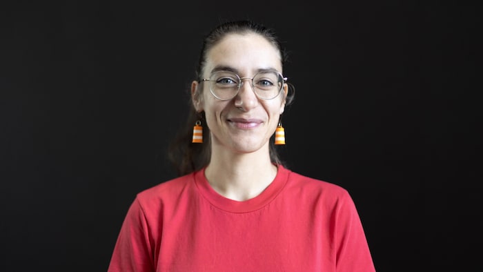 La chroniqueuse regarde la caméra en souriant.