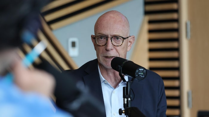 Graham Carr parle dans un micro, dans un studio de radio. 