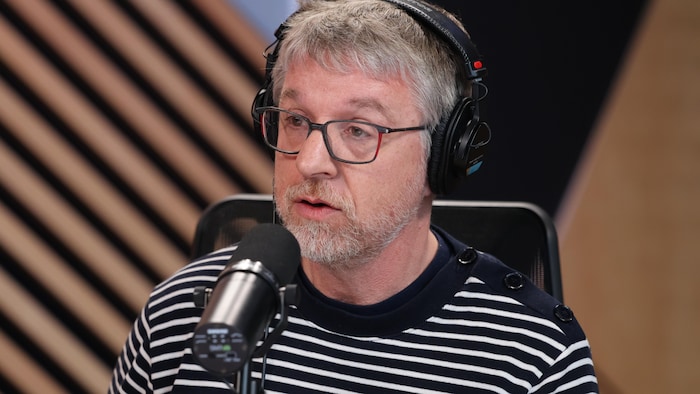 Patrick Kearney, casque d'écoute sur la tête, parle dans un micro, dans un workplace de radio.