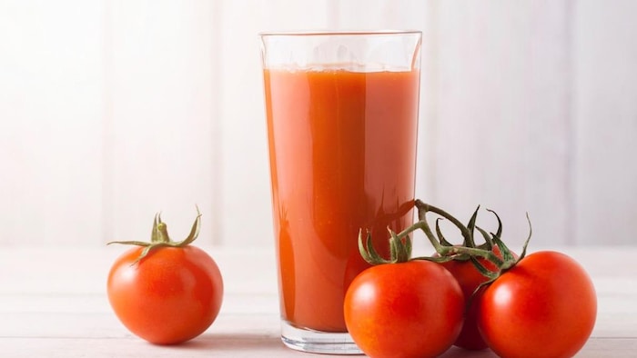 Verre de jus de tomates avec des tomates entières