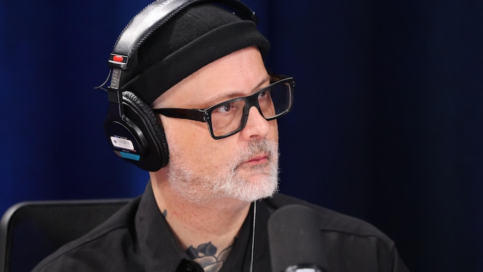 Il porte une tuque et des lunettes noires.