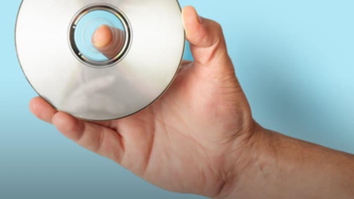Une personne tient un CD dans sa main.