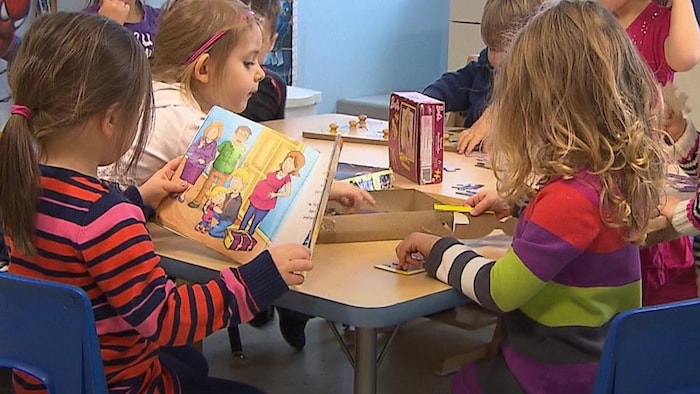 Des enfants lisent et font des casse-têtes autour d'une table.
