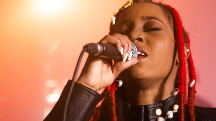 La chanteuse sur scène, yeux fermés et micro à la main. 