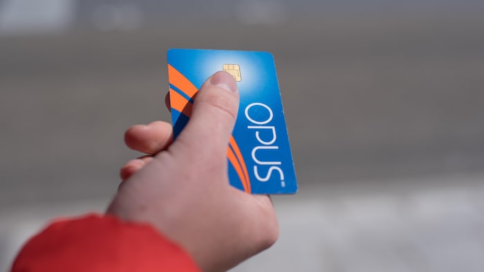 Une main tient une carte Opus.