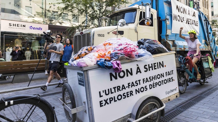 Un camion à ordure avec un chariot qui dénonce la mode jetable.