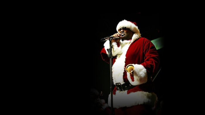 Un chanteur déguisé en père Noël, plongé dans le noir.