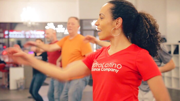 Une femme et un groupe de personnes en train de danser.