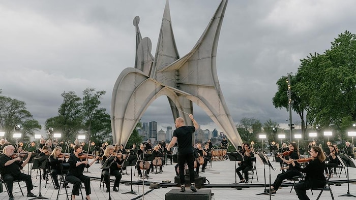 Des musiciens vêtus de noir jouent en plein air.