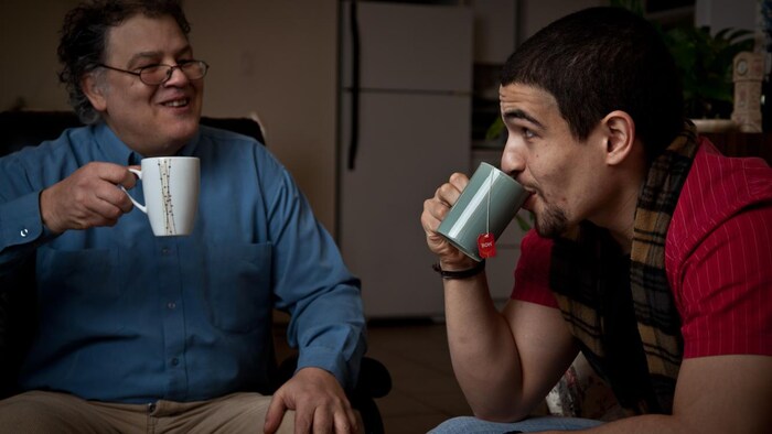 Two men drinking tea and smiling.
