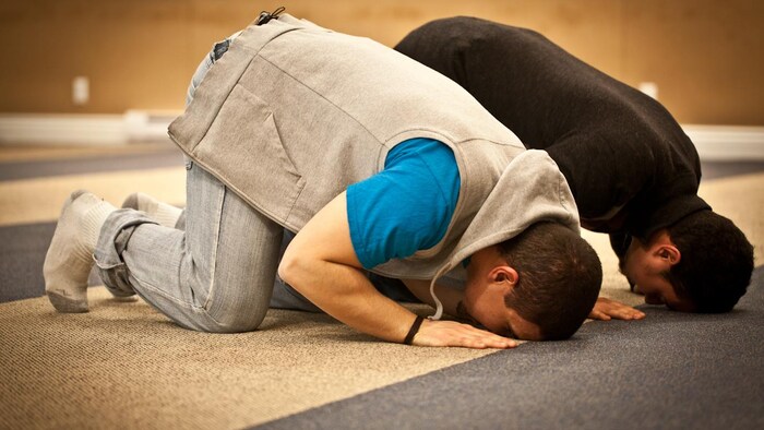Two men with their foreheads on the ground, praying.