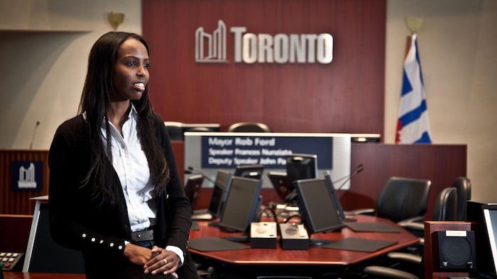 A woman sitting on a table with the Toronto logo on the background.