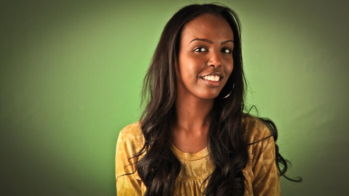A woman smiling at the camera with a green background.