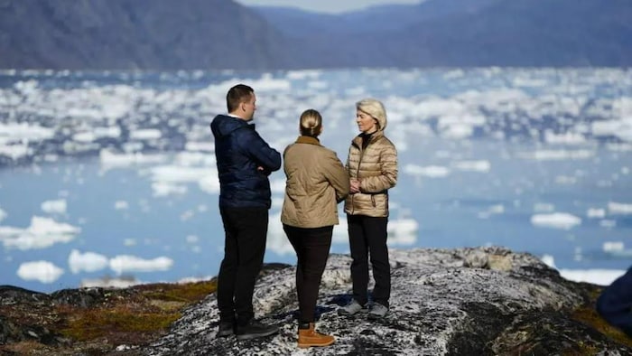 Trois personnes se tiennent devant un paysage arctique en arrière-plan.