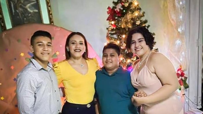 Quatre personnes posent avec un arbre de Noël en arrière-plan.