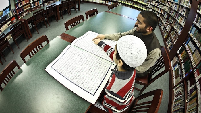 A man and a kid reading in a library.