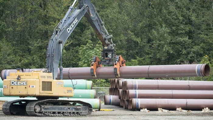 Une grue charge des tuyaux pour la construction d'un pipeline.