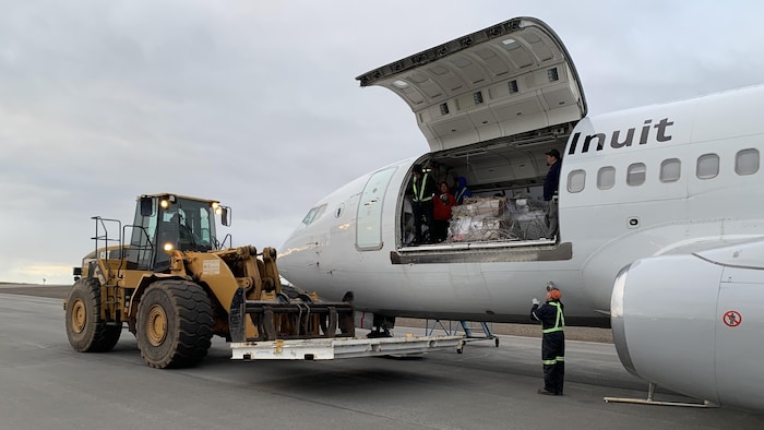 Des employés s'affairent à remplir un avion d'Air Inuit.