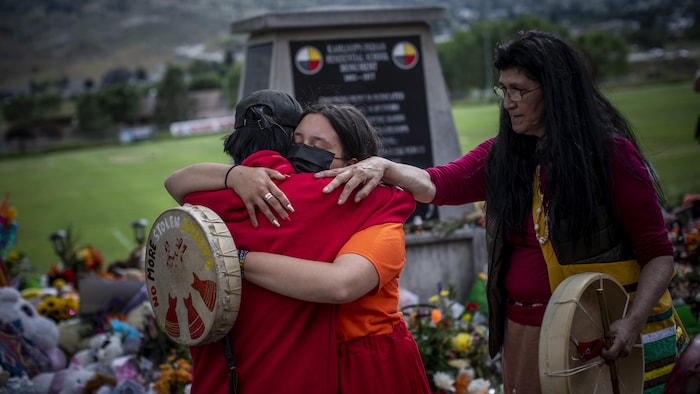 Katherine Cooper, de la Première Nation crie Mosakahiken au Manitoba, réconforte une amie devant un mémorial en honneur des enfants autochtones enterrés à Kamloops.