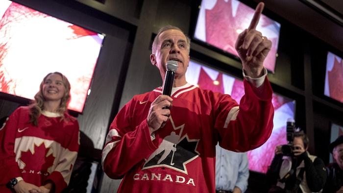 Mark Carney portant un gilet de hockey d'Équipe Canada.