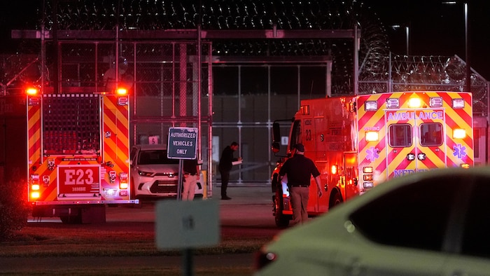 Une ambulance devant les grilles d'une prison, de nuit.
