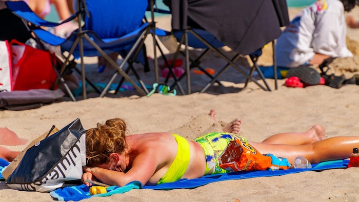 Une femme couchée sur une plage a un coup de soleil. 