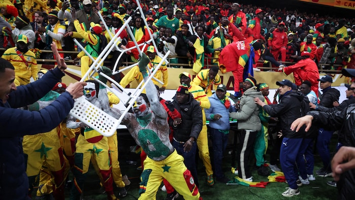Un affrontement entre des partisans du Maroc et du Sénégal lors d'un match de soccer. Deux hommes se battent avec des chaises.