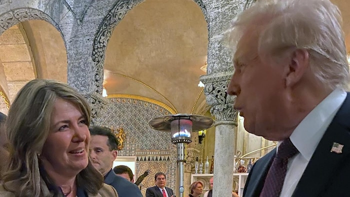 Danielle Smith parle à Donald Trump lors d'un événement mondain dans un fastueux décor.