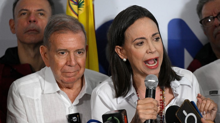 Edmundo Gonzalez Urrutia et Maria Corina Machado, assis à une table, parlent à leurs partisans.