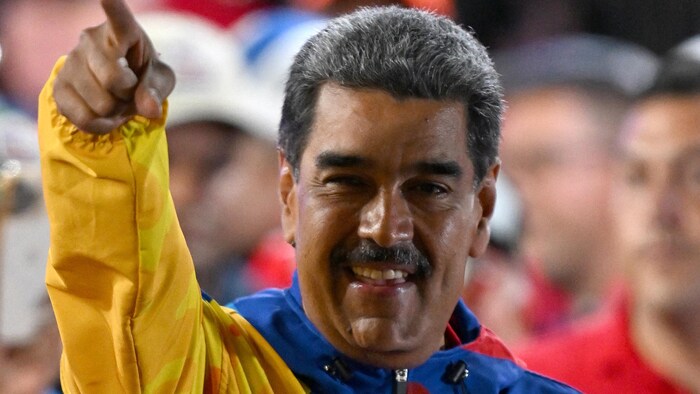 Le président vénézuélien Nicolas Maduro lève le doigt et sourit.