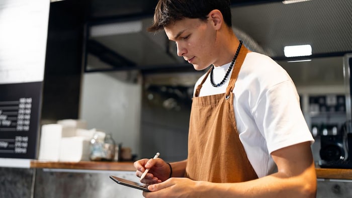 Un jeune homme travaille dans un restaurant.