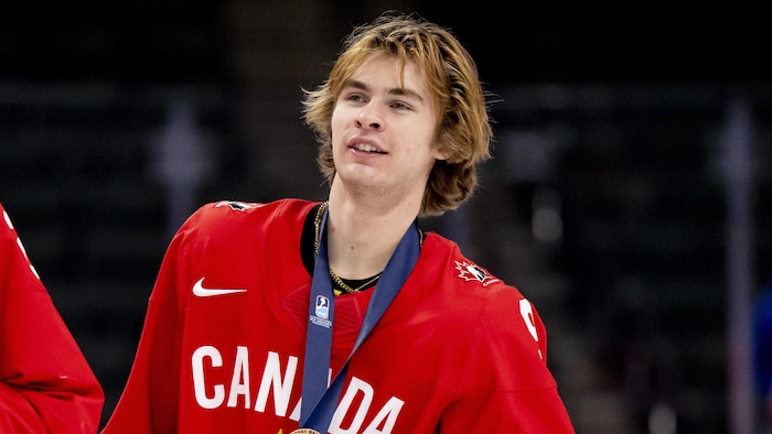Gavin McKenna portant les couleurs du Canada, une médaille au cou.