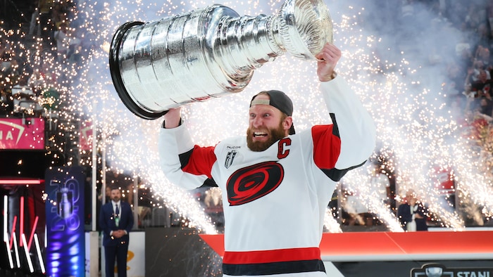 Un joueur de hockey soulève un trophée.