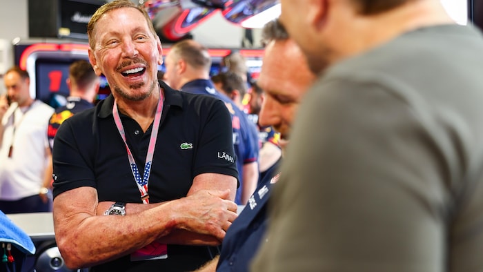 Larry Ellison, souriant, parle à un homme qui tourne le dos à la caméra.