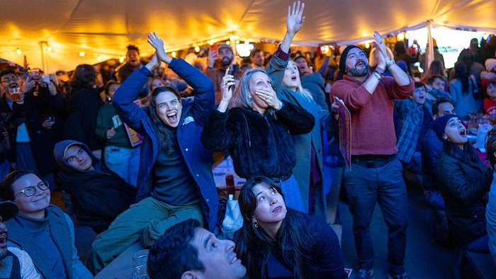 Des partisans, réunis sous un chapiteau pour regarder les résultats électoraux, célèbrent la victoire.