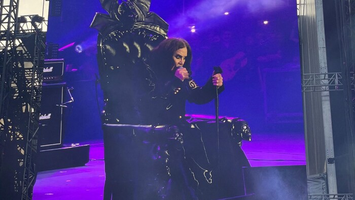 Un écran montre Ozzy Osbourne qui chante assis.