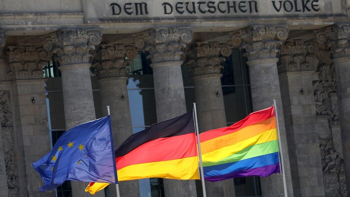 Un drapeau de l’Europe, un de l’Allemagne et un du mouvement LGBT flottent devant le Bundestag allemand à Berlin.